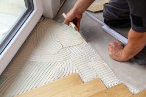 Worker laying parquet flooring. Worker installing wooden laminate flooring