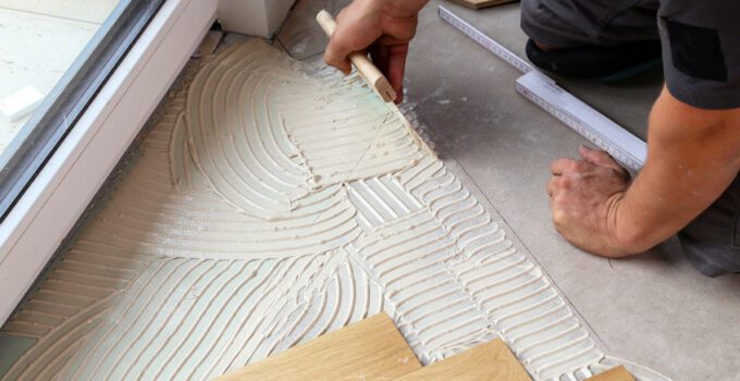 Worker laying parquet flooring. Worker installing wooden laminate flooring