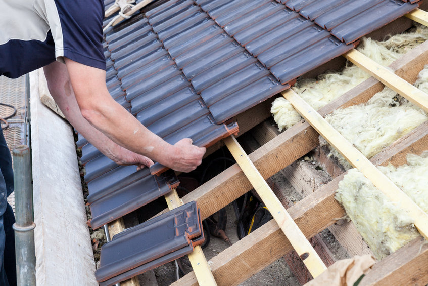 a roofer laying tile on the roof